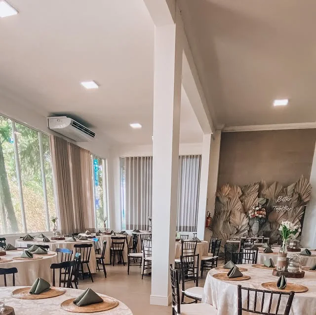 Salão do Espaço Gourmet Country com mesas postas e painel de flores
